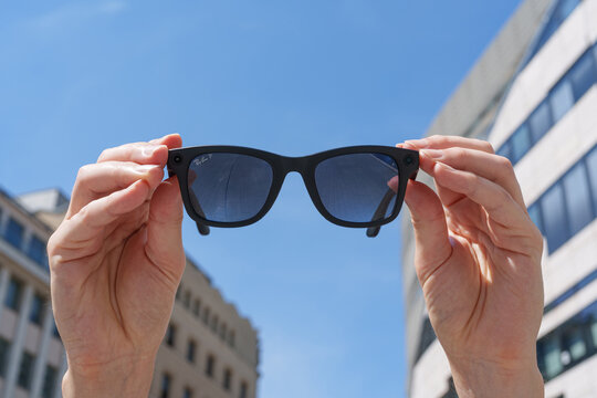 Dusseldorf, Germany - July 10 2026: Hands holding Ray-Ban Meta smart glasses against blue sky highlighting camera features