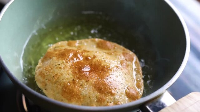 Indian bread or puri or pudi being fried in hot oil