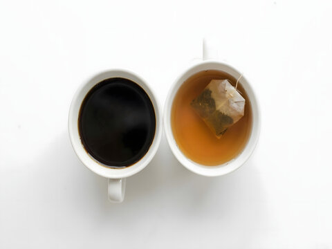 Coffee and tea in white mugs side by side for morning drinks and beverage choice, top view