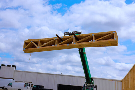 Construction workers lift wooden beam using fork lift at building site