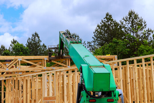 Construction equipment lifts materials on building site in wooded area