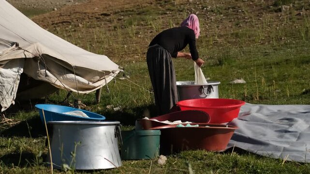 A woman strains fresh cheese curds through cloth and places them in large basins outdoors, showing traditional dairy work, handmade food production, rural life, and authentic highland culture.