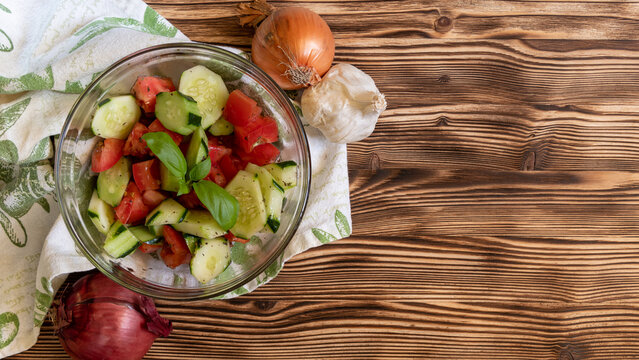 Fresh vegetable salad ingredients and finished dish on rustic wooden table