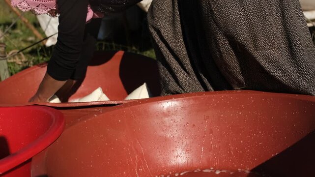 A woman strains fresh cheese curds through cloth and places them in large basins outdoors, showing traditional dairy work, handmade food production, rural life, and authentic highland culture.