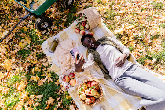 Cheerful Black woman taking selfie during sunny autumn picnic in apple orchard