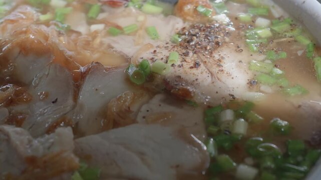 Extreme Close-up of Vietnamese Banh Canh Broth with Pork, Scallions, and Black Pepper