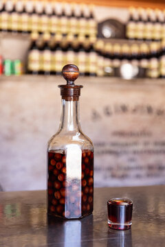 Clear bottle of infused and preserved cherries for ginja, ginjinha, traditional Portuguese cherry liqueur, next to a pour. 