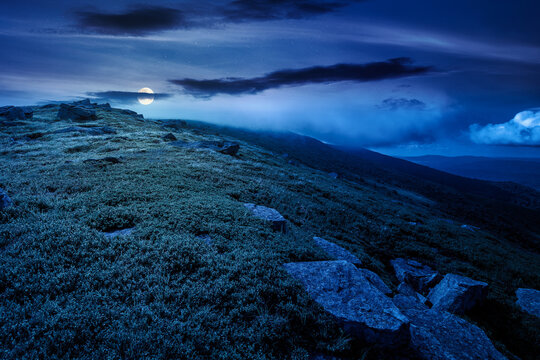 nature scenery with mountain under summer sky at night. full moon over alpine landscape of carpathian mountain with grassy slopes. low fluffy clouds on high altitude. mysterious summer vacations