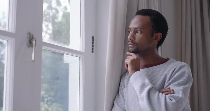 African American adult leaning by paned window, dim light urging shifting gaze, closing, looking