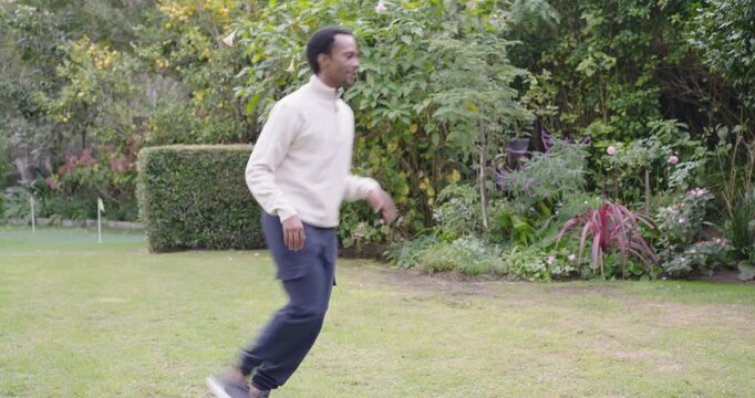 African American father and adolescent son practicing soccer in backyard with son controlling ball