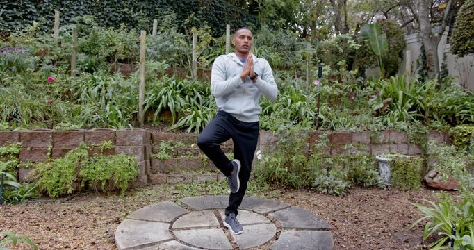 African American man starting tree pose on platform in garden with sensor stake practicing balance