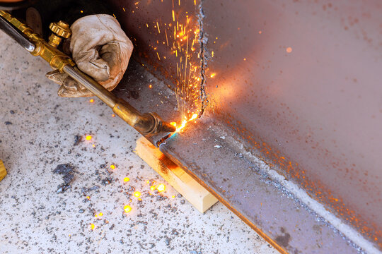 Person uses torch to cut metal in workshop at construction site