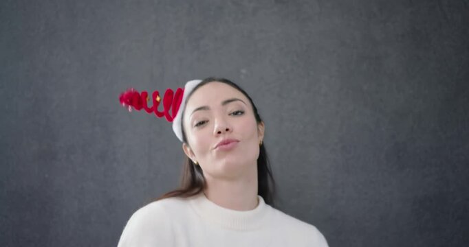 Woman tapping headband, adjusting red glasses and puckering lips in studio, showcasing sweater