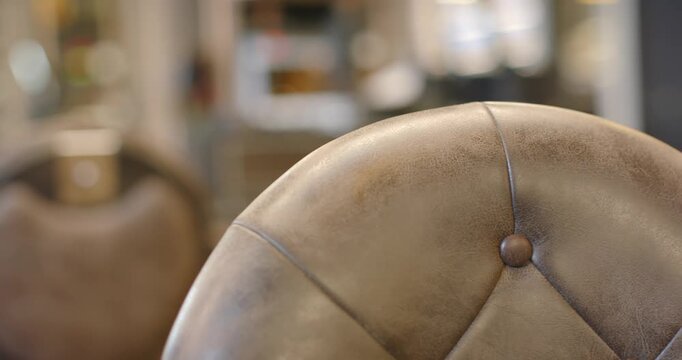 Camera is pulling back, panning and refocusing to reveal brown tufted chair and workstation