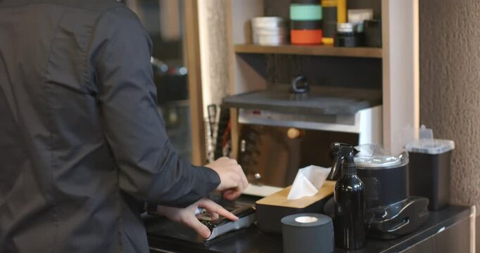 African American man barber prepping clippers, opening case, sorting shelf at salon for next client