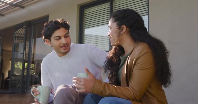 African American couple facing each other, conversing, bonding, holding ceramic mugs on porch
