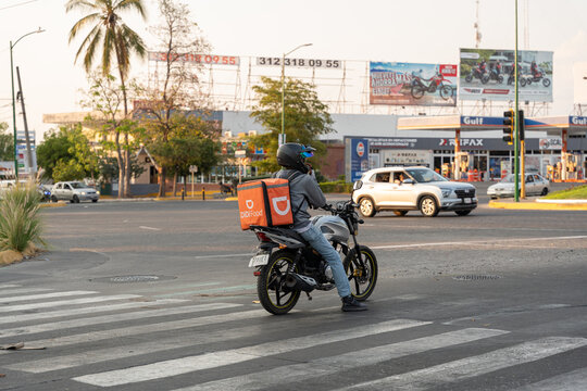 Didi driver food delivery service riding his motorbike with orange box. Sharing collaborative economy concept in South America. Guadalajar, Jalisco, Mexico, June 20, 2026.