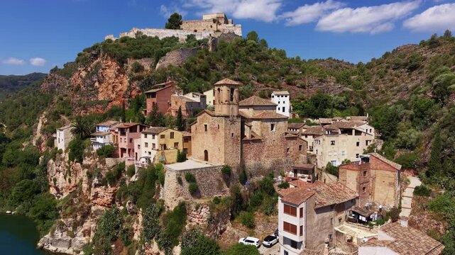 Aerial view of Miravet, a medieval village perched on rocky cliffs above the Ebro River, featuring stone houses, a Romanesque church, and the hilltop Templar castle, Tarragona, Catalonia, Spain