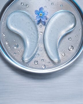 Cooling gel eye patches on metal tray with blue flower