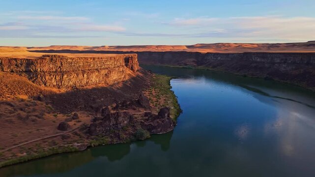 Aerial view captures the Snake River winding past golden bluffs across rural Idaho