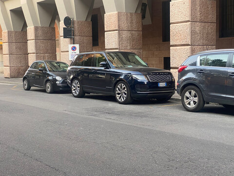 Range Rover Velar and Fiat 500 parking among other cars on a busy street in Cremona, Lombardy