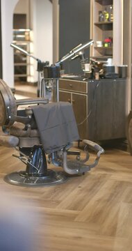 Vertical video: Person is passing while camera is sliding forward to reveal shop chair and tools