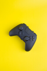 Vertical flat lay of blank black gamepad controller mockup on yellow background with copy space for gaming design.  © wibiwisnu