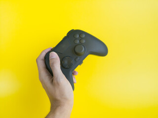 Hand Holding Blank Black Gamepad Controller Mockup on Yellow Background  © wibiwisnu