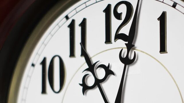 Close-up time lapse shows decorative black clock hands rapidly sweeping over a classic white clock face. The swift movement symbolizes accelerated time passage.