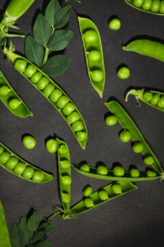 Fresh green peas pattern on black textured background. Vertical top view composition.