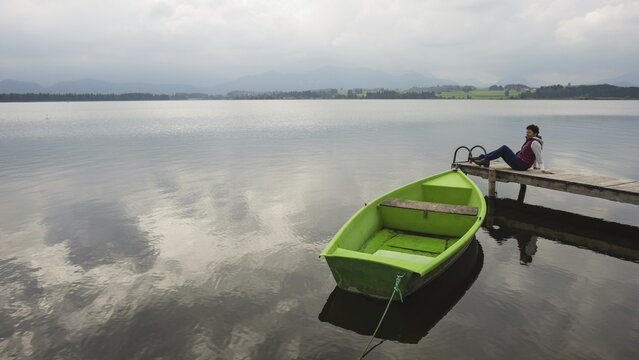 Woman 50+, wooden jetty, green rowing boat, Hopfensee, Hopfen am See, near F&uuml;ssen, Ostallg&auml;u, Allg&auml;u, Bavaria, Germany