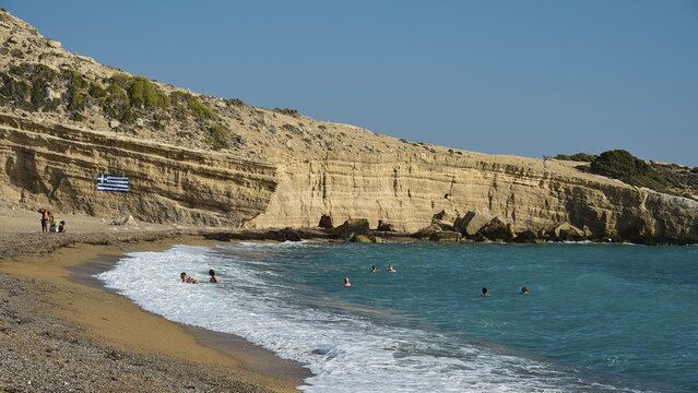 Beach with bathers next to rocky coast and clear blue water under a sunny sky, Cape Fourni, Fourni Beach, near Monolithos village, Rhodes, Dodecanese, Greek Islands, Greece