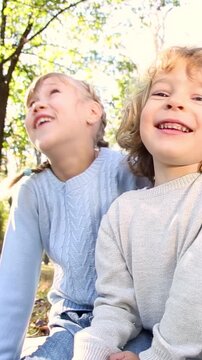 Happy children playing outdoors in the autumn park. Three girl friends having fun outside. Vertical video, slow motion