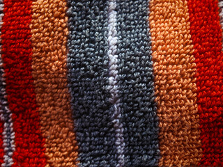 Fototapeta premium Looping textured fabric showing vibrant red, orange, grey, and white stripes creating a tactile and detailed surface