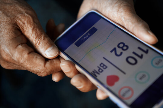 Senior hands holding smartphone with fitness tracker display