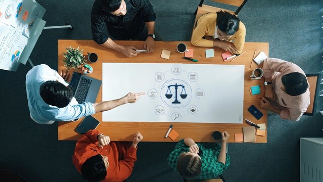 Dynamic meeting scene showcasing a team engaged in discussion around a visual presentation symbolizing balance and equality in a collaborative workspace. Raster