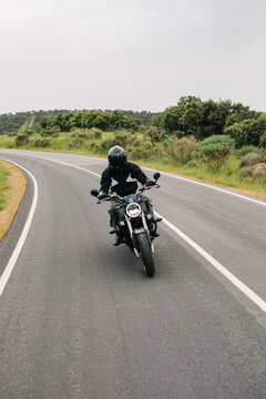 Motorcyclist riding on a winding rural road in summer