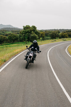 Man riding motorcycle on winding road through countryside