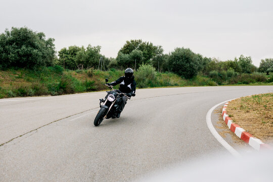 Man riding motorcycle on curving road in countryside