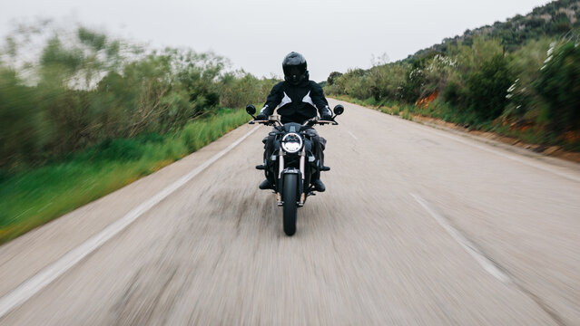 Motorcyclist riding on open road through countryside