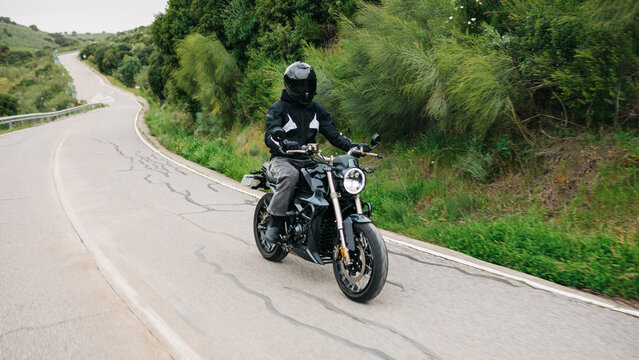 Man riding motorcycle on winding countryside road in nature