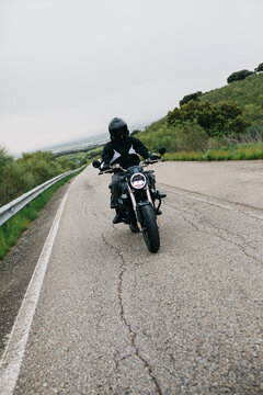 Motorcyclist riding on winding rural road in misty day