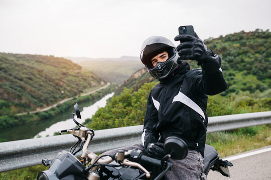 Motorcyclist taking selfie on scenic mountain road view