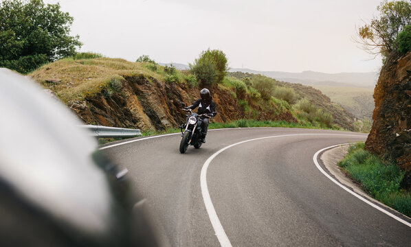 Man riding motorcycle on winding road in rural landscape