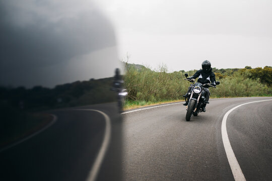 Motorcyclist riding on curving road in rural landscape
