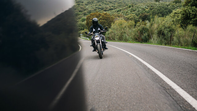 Motorcyclist riding A winding road through green hills