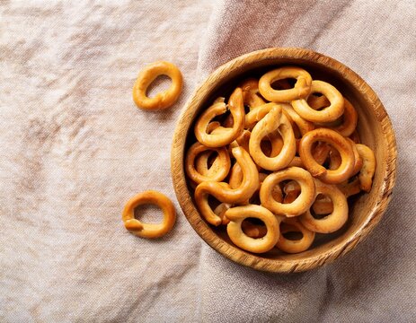 traditional italian snack taralli or tarallini in wooden bowl over light linen napkin background rustic shot of taralli appetizer with copy space top view or flat lay