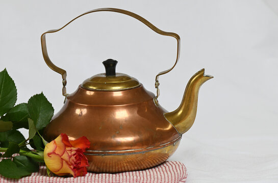Still life of a teapot, a rose and an oven glove
