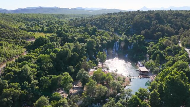 High altitude aerial panorama of emerald river and surrounding forest landscape