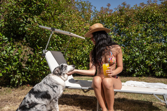 Woman relaxing outdoors with a dog and a drink